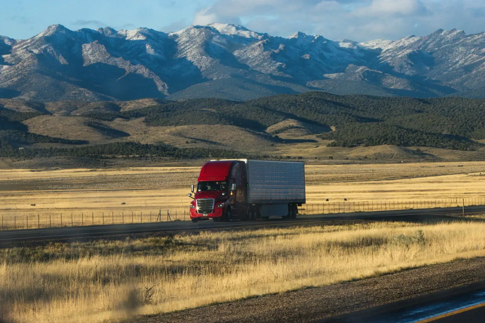 Freight truck on an open highway with snow-capped mountains behind
